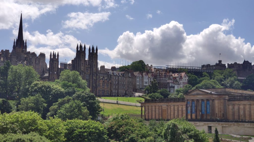 Ein Foto aus der Innenstadt von Edinburgh - im Vordergrung ist ein Park zu erkennen und im Hintergrund sieht man verschiedene alte Gebäude
