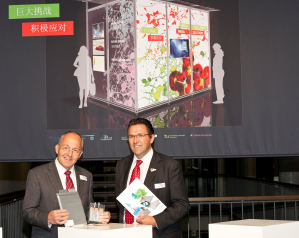 Dr. Gerhard Hrpel vom MEET-Batterieforschungszentrum (links) und WWU-Prorektor Prof. Dr. Stephan Ludwig vor einer Illustration des Wissenschafts-Containers.