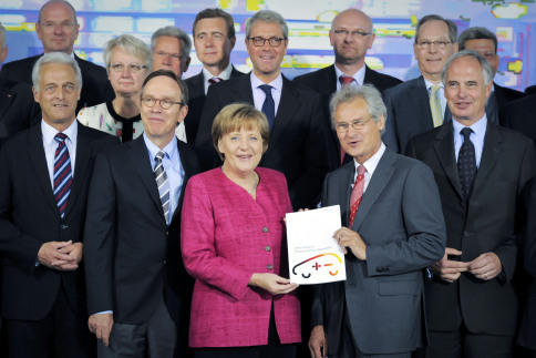 Prof. Dr. Martin Winter (hinten, 3. v. r.) bei der bergabe des zweiten Berichts der Nationalen Plattform Elektromobilitt in Berlin. Bundeskanzlerin Angela Merkel (Mitte) nahm den Bericht entgegen.