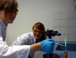 Annika Kruse (links) und Sybille Niemeier analysieren die Flammenfarbe von Kupfer mit einem Spektroskop nach Kirchhoff und Bunsen.
