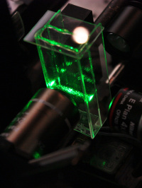 Versuchsaufbau zum Nachweis des Trampolins aus Licht – innerhalb der Glaskvette wurde die Laserlichtbarriere durch streuende Partikel sichtbar gemacht.