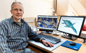 Dr. Oliver Hampe - im Hintergrund links die Knochen des Gronausaurus, rechts die Rekonstruktion eines nahen Verwandten des neu entdeckten Schwimmsauriers.