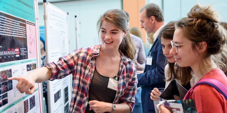 Foto einer Gesprächssituation zwischen Nachwuchswissenschaftlerinnen während einer Posterpräsentation bei einem wissenschaftlichen Symposium