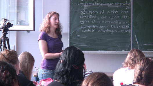 Bild einer Lehrerin vor einer Tafel stehend