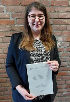 Portrait-Foto of Dana Atzpodien with her doctoral thesis in hand