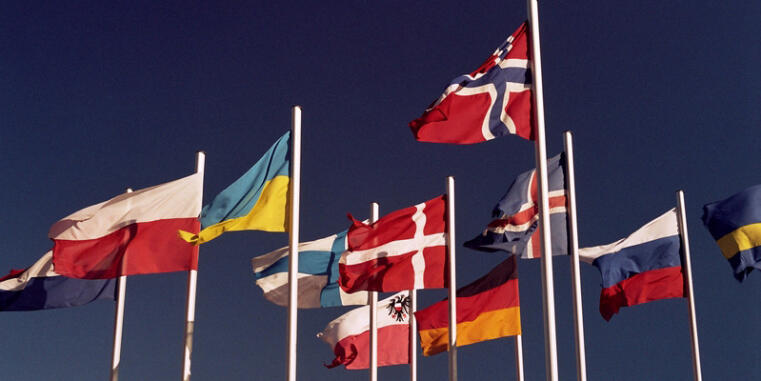 Flaggen von verschiedenen Ländern vor einem blauen Himmel