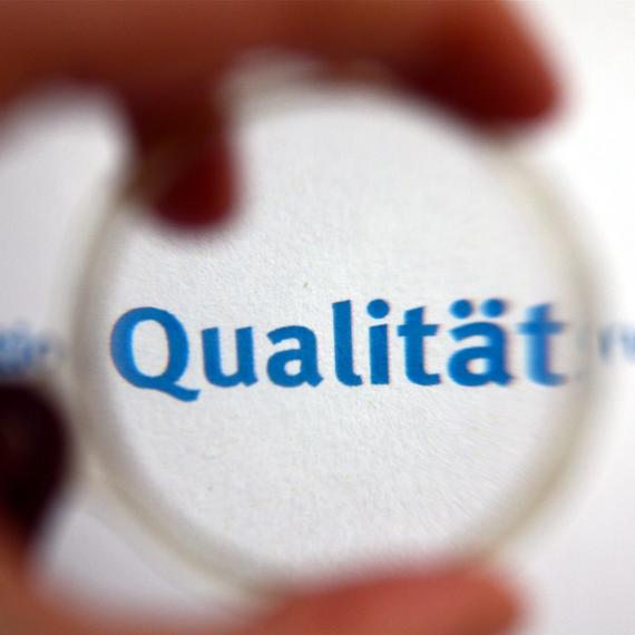 Word "Qualität" seen through a magnifier
