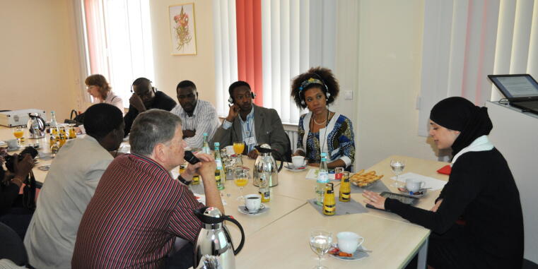 Delegierte aus Tansania sitzen um einen Tisch mit Kaffeegeschirr vor Kopf sitzt Dr. Dina El Omari