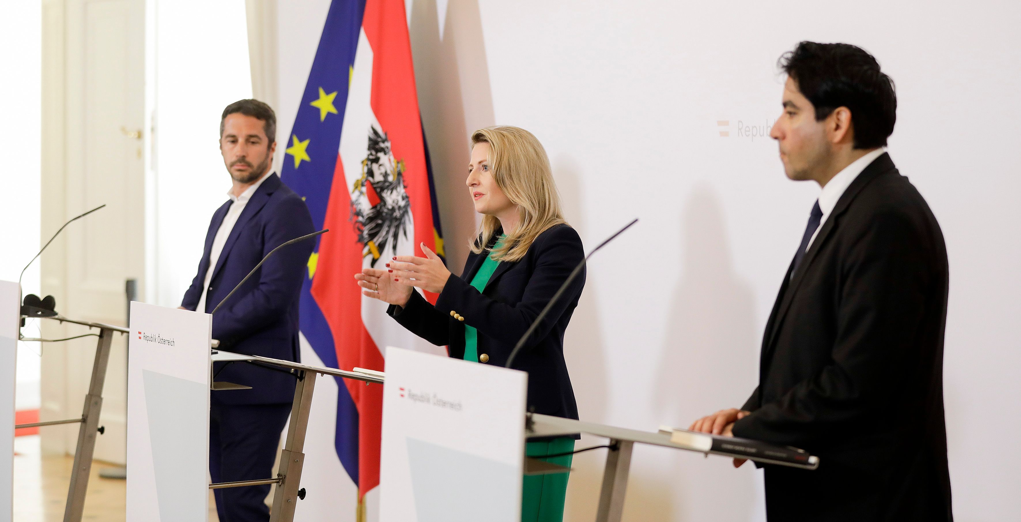 Lorenzo Vidino, Susanne Raab,  Mouhanad Khorchide stehen vor Rednerpulten, im Hintergrund sind die österreichische und die europäische Flagge zu sehen