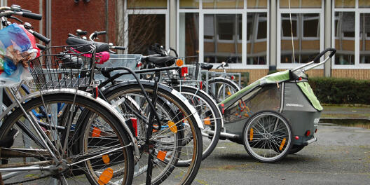 Fahrrad mit Kinderanhänger vor einem Insttut