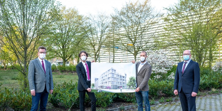 Rector Prof. Johannes Wessels (left) and Head of Administration Matthias Schwarte (right) present the plans for the new research building with mathematicians Prof. Mario Ohlberger (2nd from left) and Prof. Thomas Nikolaus. The visualization, produced by the Münster office of North Rhine-Westphalia’s Buildings and Real Estate Management Department, gives a first impression of the building which will be constructed near Coesfelder Kreuz.<address>© WWU - Michael Möller</address>