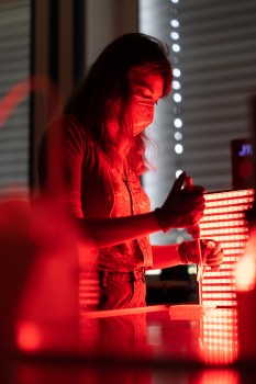 Die Doktorandin Saskia Frank arbeitet im abgedunkelten Labor und unter Nutzung von rotem Licht mit einem Hydrogel aus fluoreszierenden Proteinen.<address>© WWU - Peter Leßmann</address>