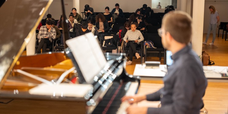 In der Gehörbildungsprüfung spielt Tim Sandkämper den Bewerberinnen und Bewerbern Tonfolgen am Klavier vor. Die Prüflinge müssen das Gehörte zu Papier bringen.<address>© Uni MS - Johannes Wulf</address>