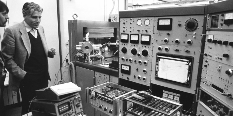 Das Schwarz-weiß-Bild zeigt Prof. Dr. Borwin Grauert, der im Jahr 1978 im Zentrallaboratorium für Geochronologie neben einem Festkörpermassenspektrometer mit elektrischem Bedienapparat steht.<address>© Universitätsarchiv</address>