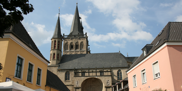 Ein Dom im Zentrum des Bildes, links und rechts zwei Häuser mit gelber und rosaner Fassade. 