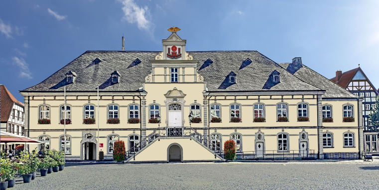 Symmetrisches historisches Rathaus mit heller Fassade, zentraler Freitreppe und hohem Walmdach auf einem offenen Marktplatz unter blauem Himmel.