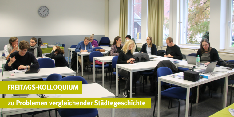 A group of participants sitting at white tables in a bright seminar room, focused on working on laptops and taking notes. A yellow banner in the foreground displays the text: FREITAGS-KOLLOQUIUM zu Problemen vergleichender Städtegeschichte.