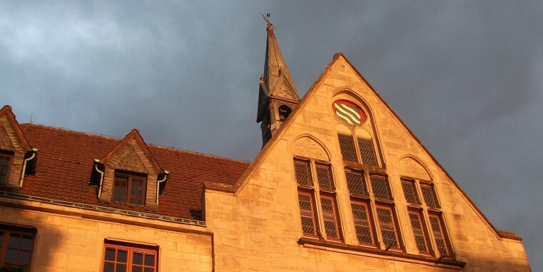 Architectural shot of a building with a tower and coat of arms.