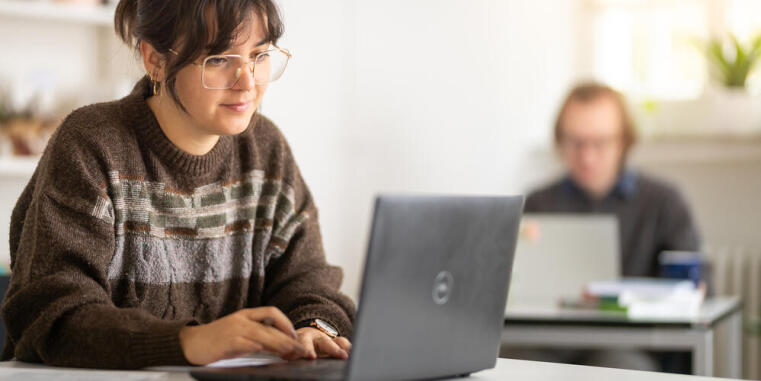 Teilnehmer und Teilnehmerin an Laptops im Seminarraum OG 2