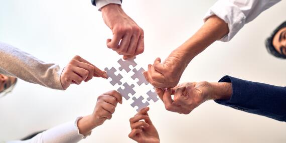 Group of business workers with hands together connecting pieces 