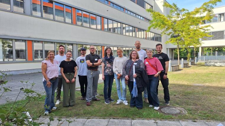 Gruppenfoto von 11 Lehrkräften im sonnenbeschienenen Innenhof des PharmaCampus.