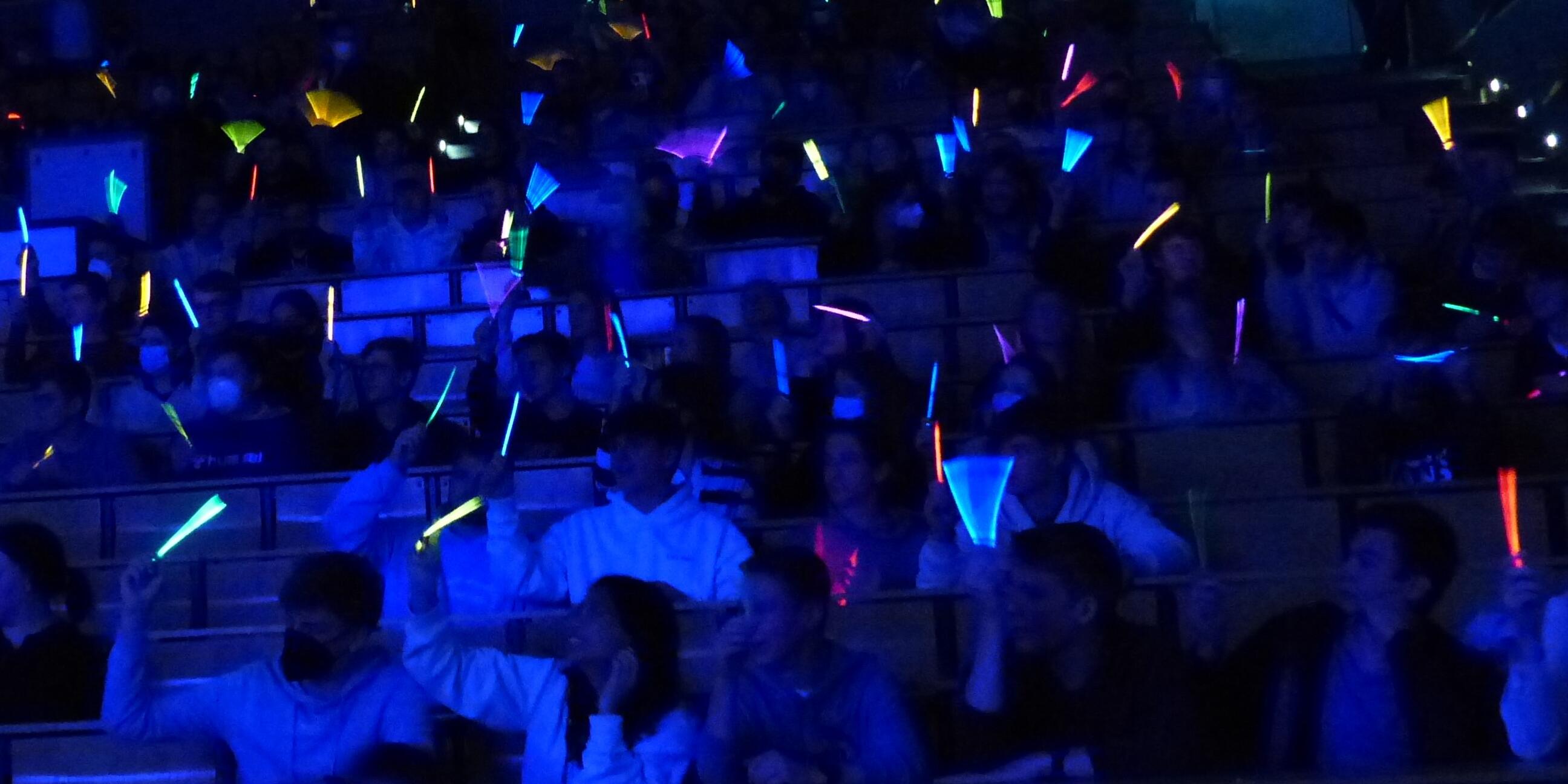 Besucher halten Knicklichter in die Luft.