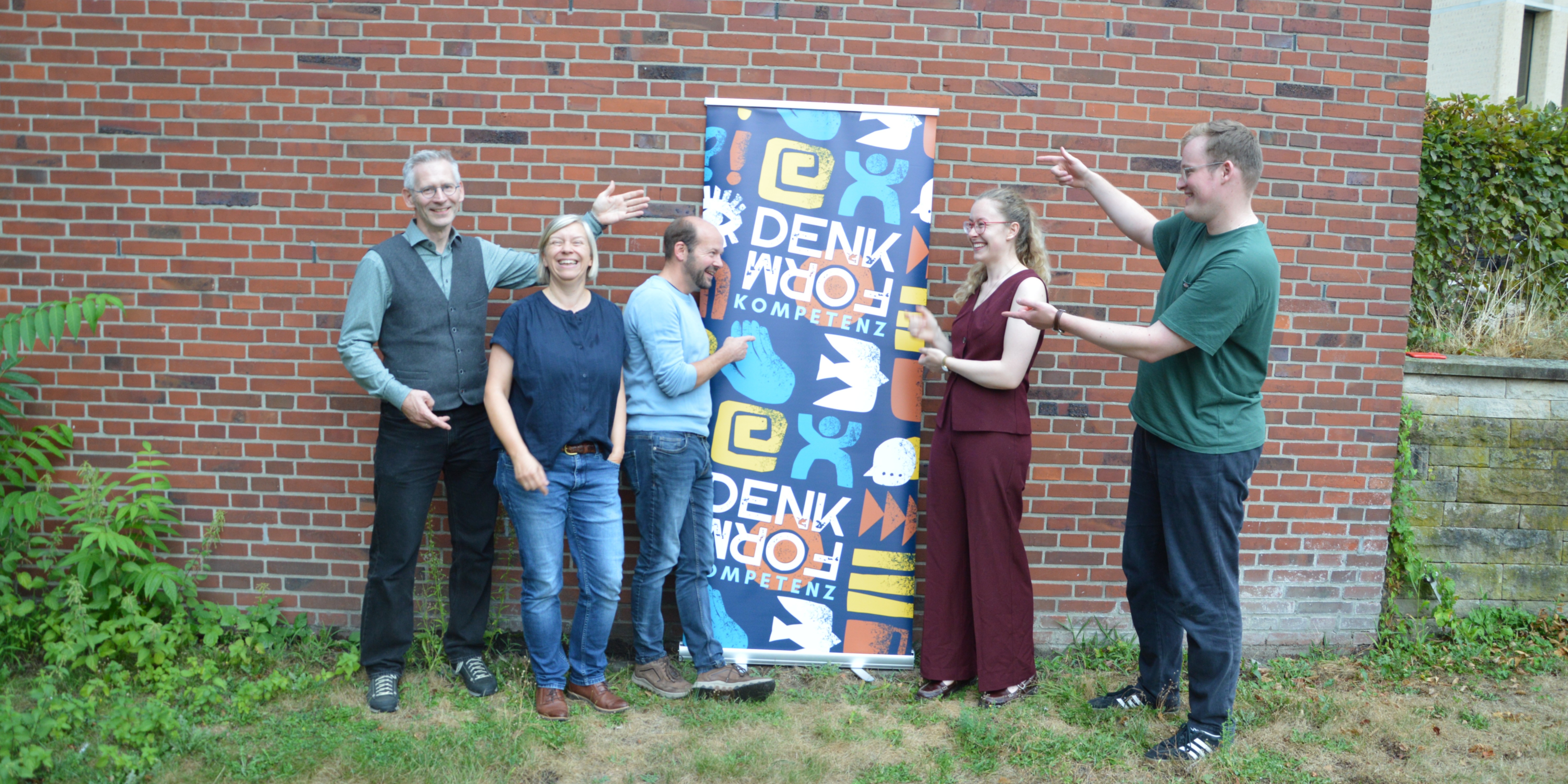 Das Vorbereitungsteam vor dem Plakat zur Werkstatt