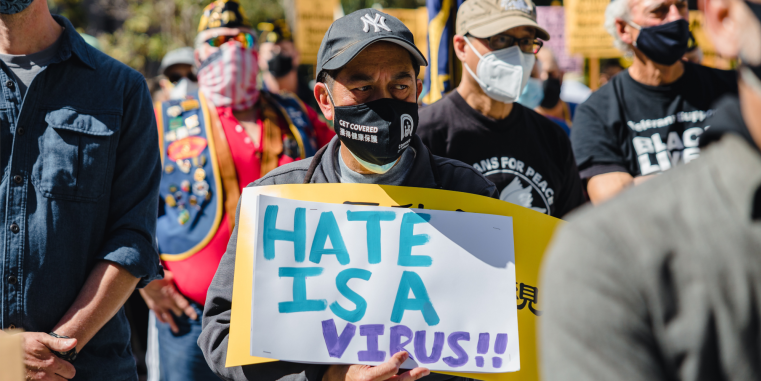 Ein Protestierender trägt ein Schild mit der Aufschrift "Hate Is A Virus"