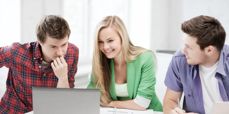 Drei Studierende, zwei Männer und eine Frau, betrachten Inhalte auf einem Laptop