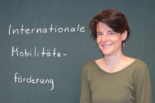 Weinberg / Foto vor einer Tafel mit der Aufschrift "Internationale Mobilitätsförderung"