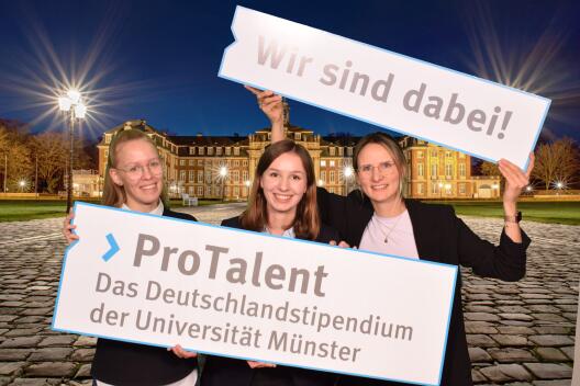 Foto von Teilnehmerinnen der Stipendienfeier 2024 mit Schild: "ProTalent. Das Deutschlandstipendium der Universität Münster".