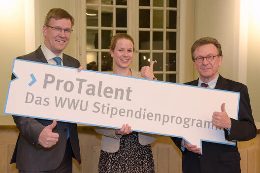 Foto von Herrn Prof. Dr. Wessels, Rektor der Universität Münster, einem Vertreter der Sitftung WWU und einer Stipendiatin. Sie halten ein Schild, auf dem "ProTalent - Das WWU Stipendienprogramm" steht, hoch.