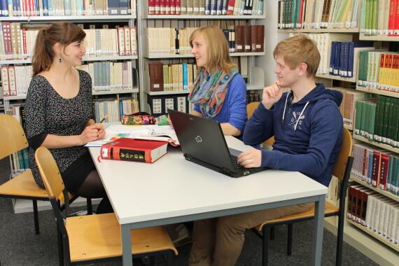 Drei Studierende in der Institutsbibliothek