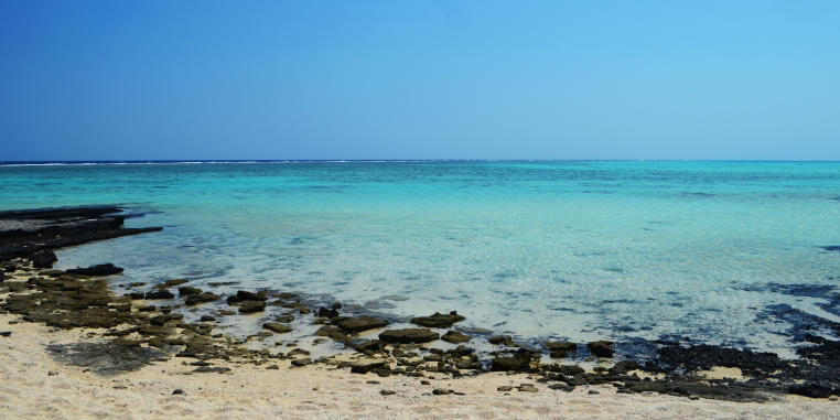 Der Blick von einem Strand auf das blaue Wasser des Meeres.