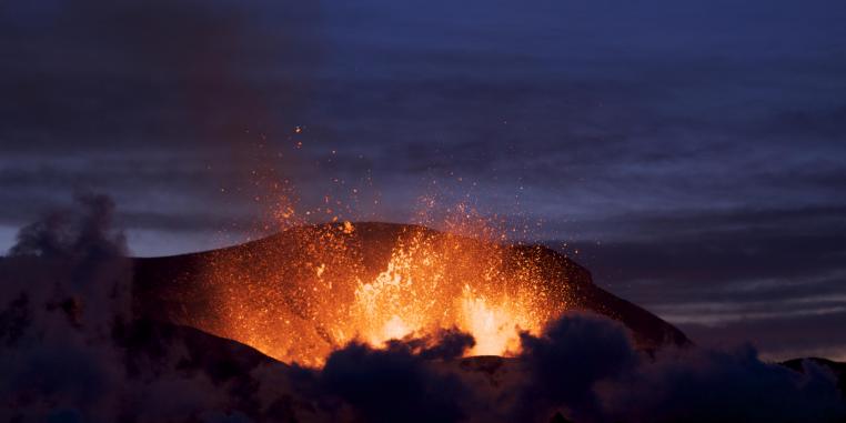 Ein Lava speiender Vulkan in der Abenddämmerung.
