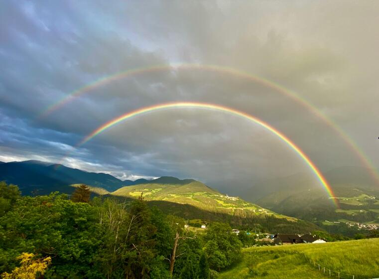 Ein doppelter Regenbogen spannt sich über den Horizont einer Bergwelt