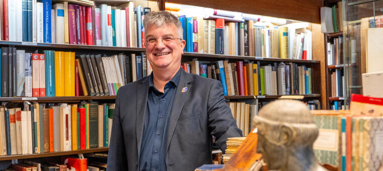 Ein Mann steht vor einem Regal voller Bücher.