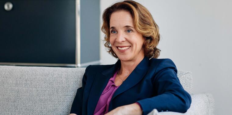 Eine Frau sintzt in einem Raum auf der Couch.