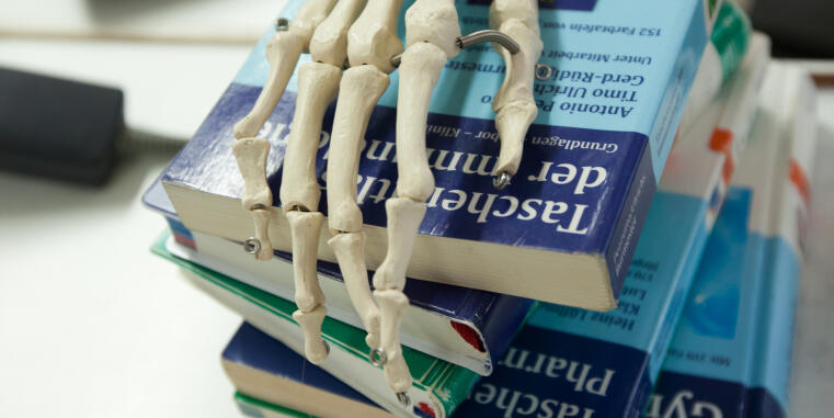 Skeleton hand on pile of books