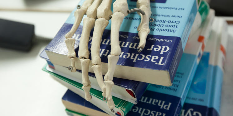 Stack of books with skeleton hand