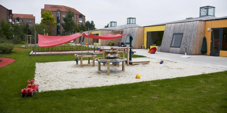Outdoor area of one of the day care centre Chamäleon with sand playground and climbing frame