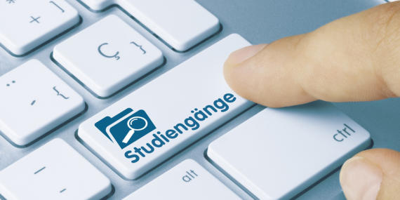 keyboard with finger pushing on key labelled "Studiengänge" or study programmes