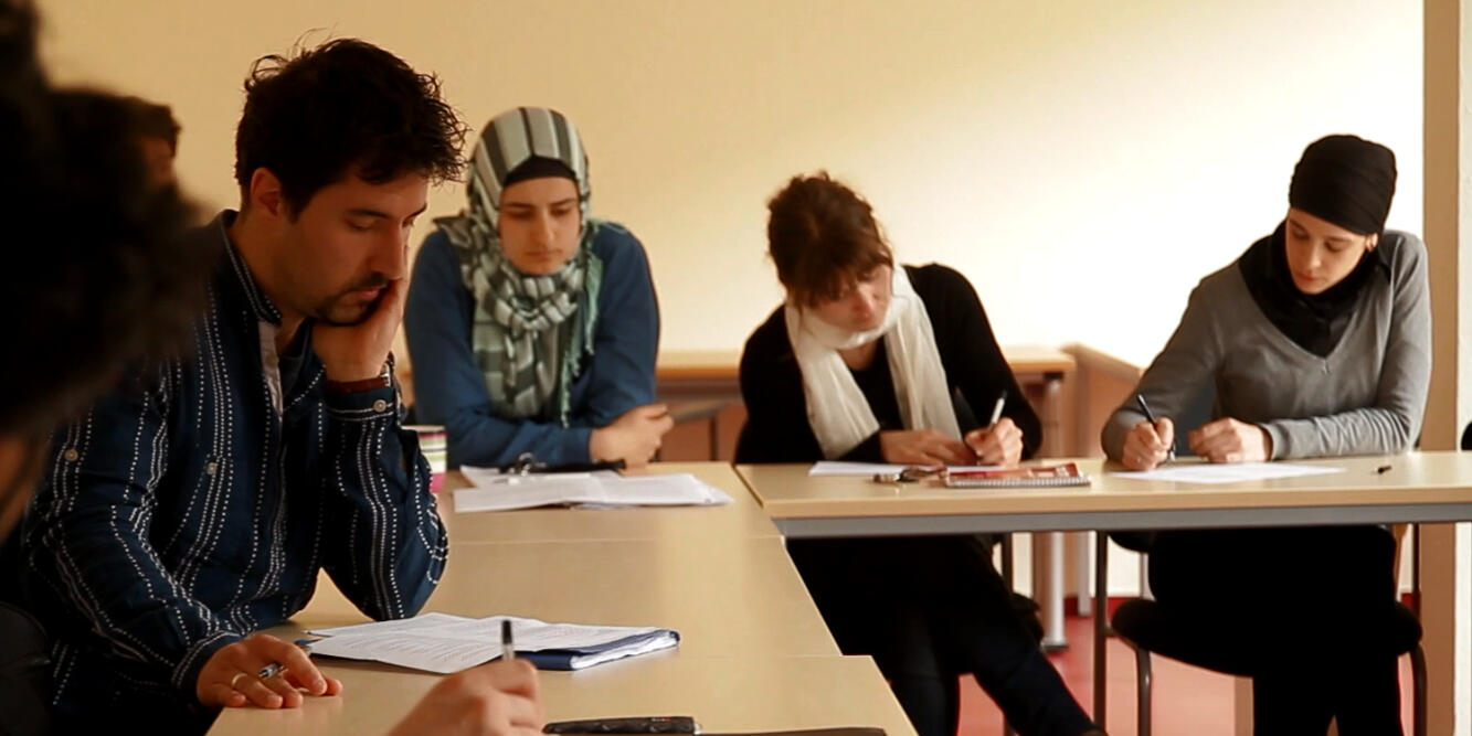 Bildausschnitt aus dem Imagevideo zeigt Studierende schreibend an Tischen 