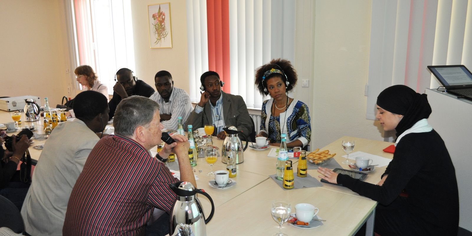 Delegierte aus Tansania sitzen um einen Tisch mit Kaffeegeschirr vor Kopf sitzt Dr. Dina El Omari
