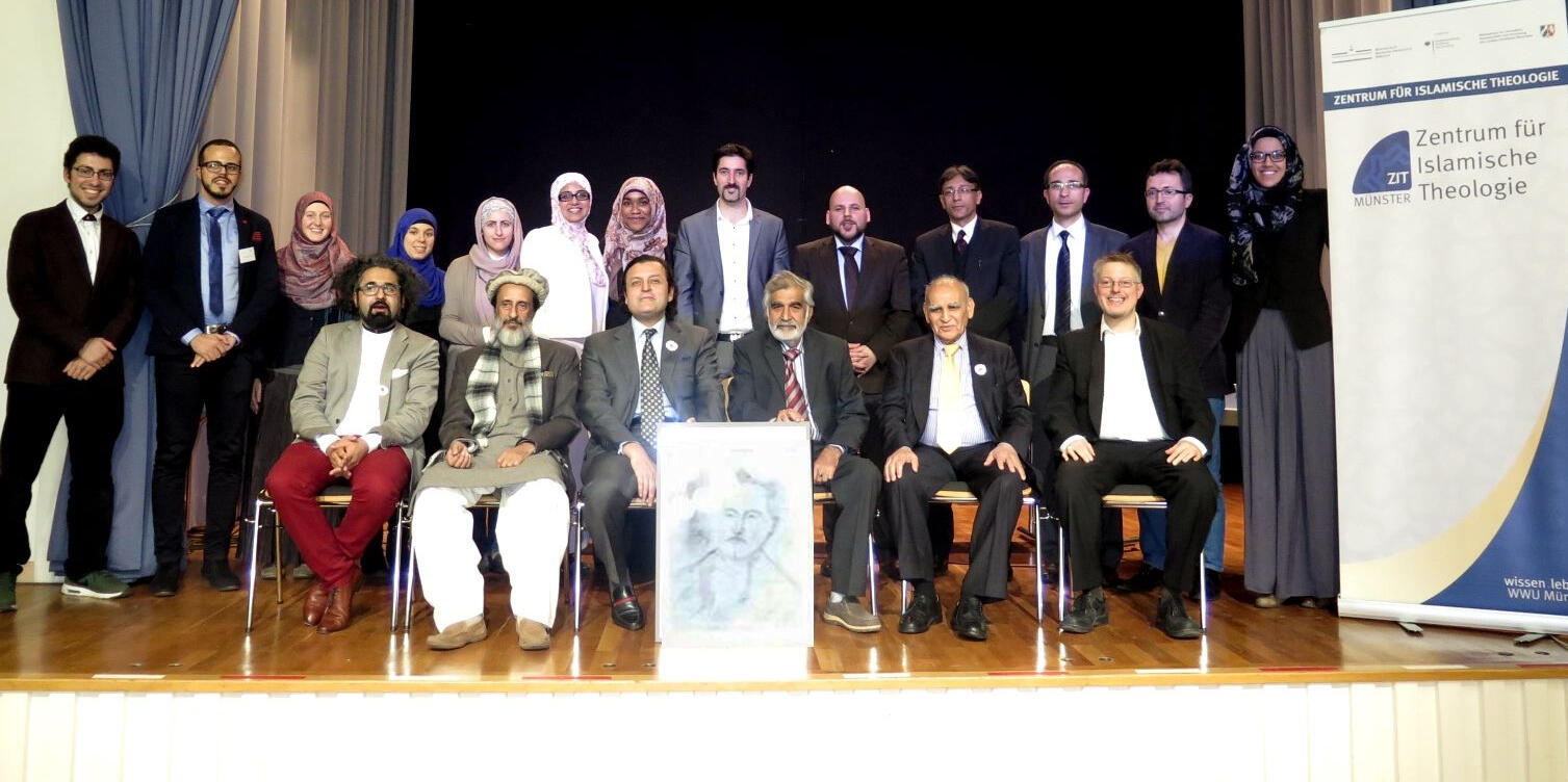 Die Referenten und Organisatoren des Symposiums stehend und sitzend, rechts das Roll-up des ZIT, vor der ersten Reihe ein gezeichnetes Porträt von Muhammad Iqbal