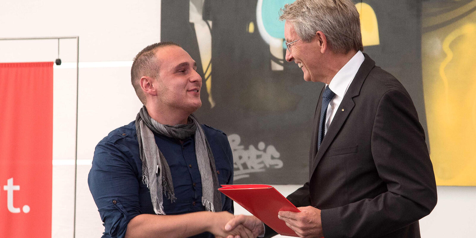 Heinz Mölder schüttelt dem Preisträger Umut Ali Öksüz die Hand