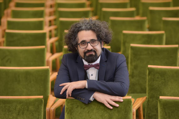Prof. Dr. Ahmad Milad Karimi sitzend in mitten von grünen Stühlen