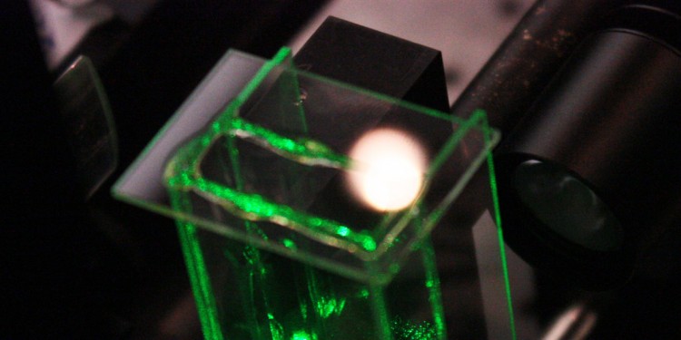 Experimental setup for the creation of a photophoretic trampoline; inside the glass cuvette, the laser light sheet was visualized by scattering particles.<address>&copy; WWU/AG Nichtlineare Photonik</address>