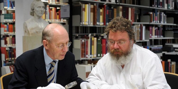 Prof. Dr. Rolf Wiermann (links) und Reinhard Feldmann begutachten einen der historischen Gartenpläne.<address>© WWU - Grewer</address>