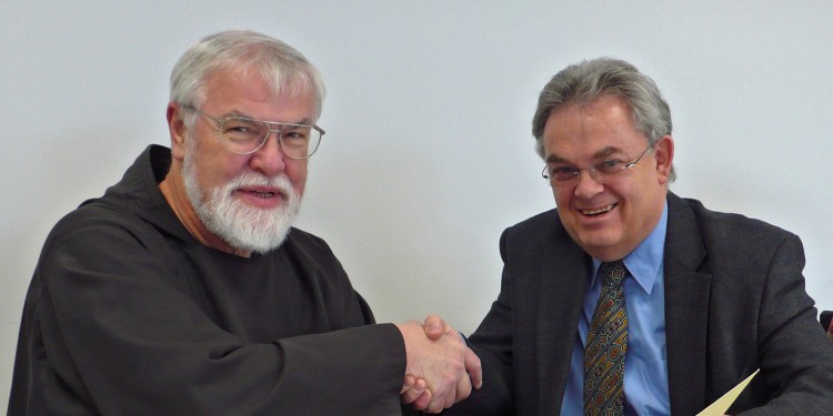 Pater Richard Dutkowiak (links) und Dr. Klaus Hilgemann besiegeln mit Handschlag die Vertragsunterzeichnung über die wertvolle Dauerleihgabe.<address>© WWU</address>